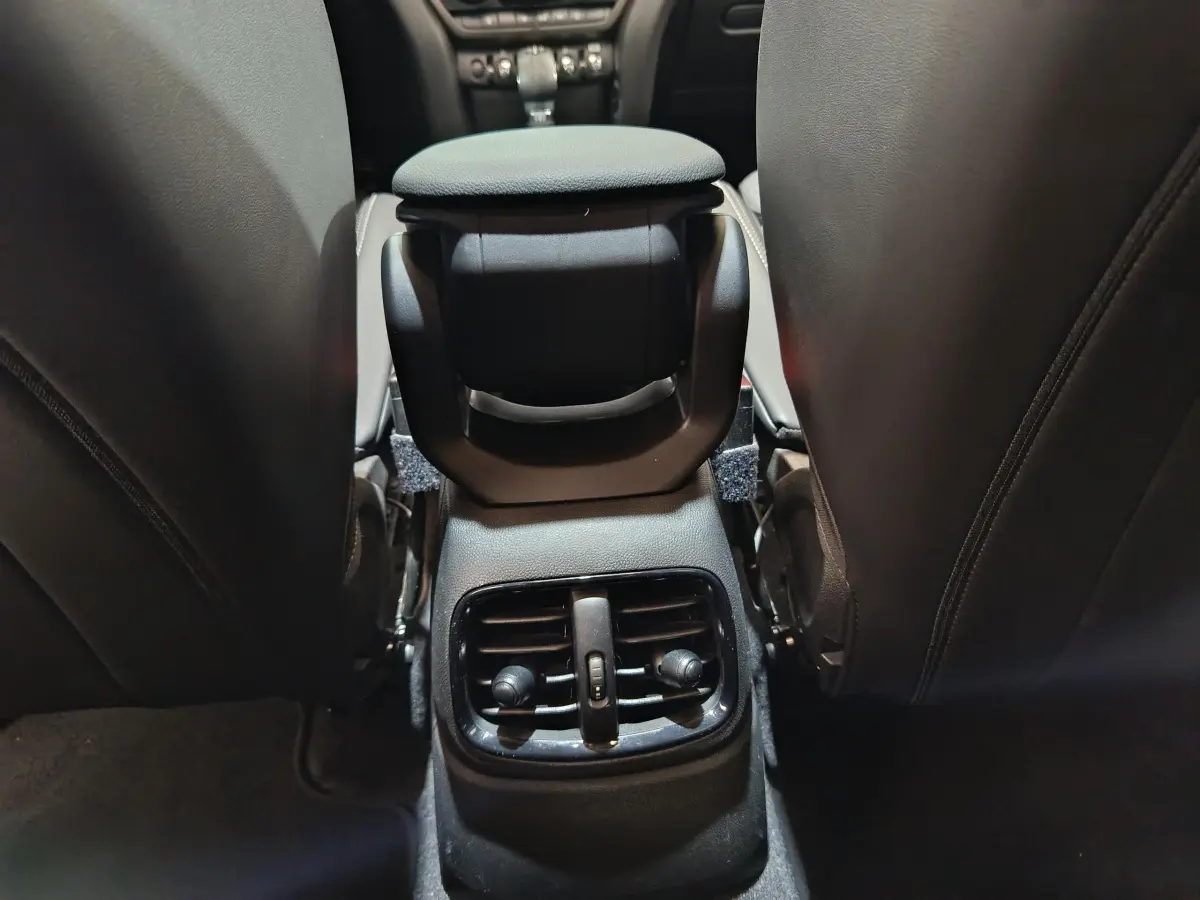 Détail de la console centrale arrière avec aérateurs, entre les sièges noirs d'une MINI Countryman blanche.