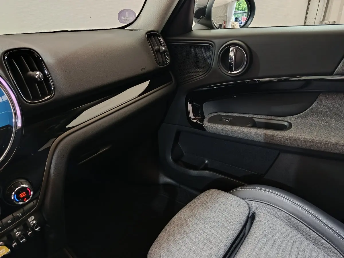Intérieur côté passager du MINI Countryman blanc 2021, avec tableau de bord noir et garniture tissu gris.