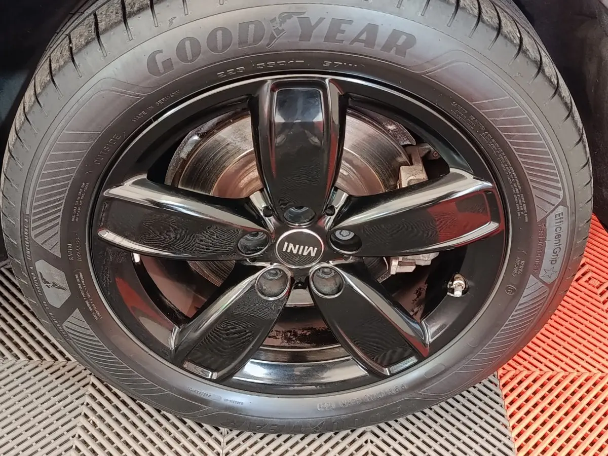 Gros plan sur la jante noire brillante à cinq branches du MINI Countryman blanc, pneu Goodyear visible.