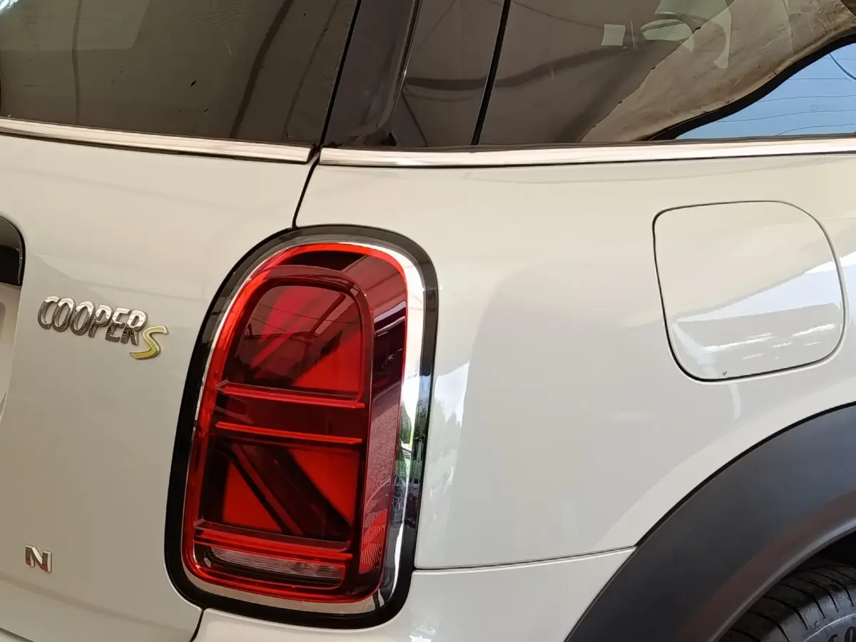 Gros plan sur le feu arrière gauche rouge et la trappe à carburant d'un MINI Countryman Cooper S blanc, vue arrière côté gauche.