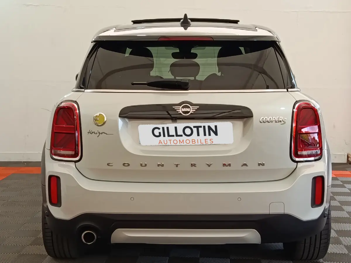 Vue arrière d'une MINI Countryman Cooper S blanche avec logo Horizon et feux arrière rouges dans un garage.