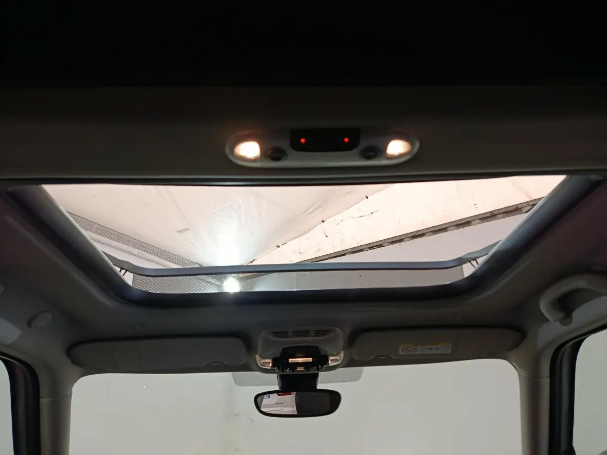 Toit ouvrant panoramique ouvert vu de l'intérieur avant du MINI Countryman blanc 2021 avec rétroviseur central visible