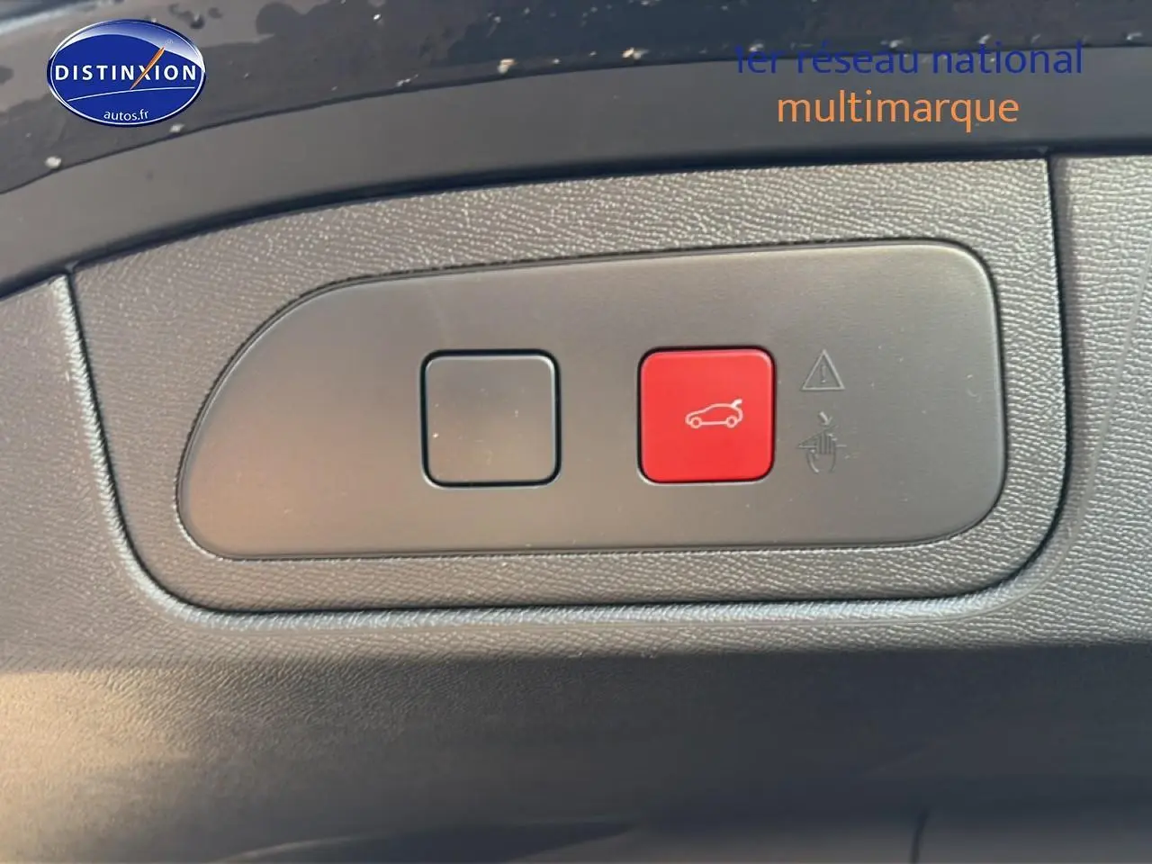 Gros plan sur bouton rouge d'ouverture du coffre dans l'habitacle du DS7 noir 2026, côté conducteur.
