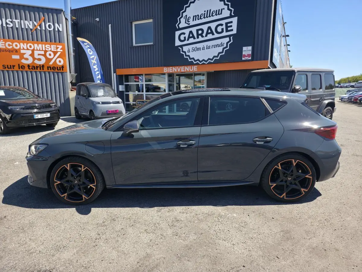Vue de profil droit d'une CUPRA Leon 1.5 e-Hybrid bleu foncé avec jantes alliage 19'' cuivrées, vitres arrière surteintées.