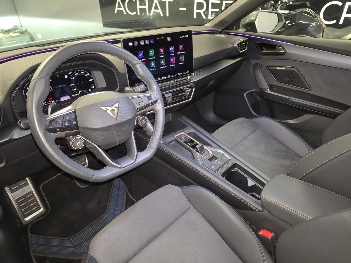 Intérieur avant de la CUPRA Leon 2024, vue côté conducteur, tableau de bord noir avec écran tactile et volant multifonction.