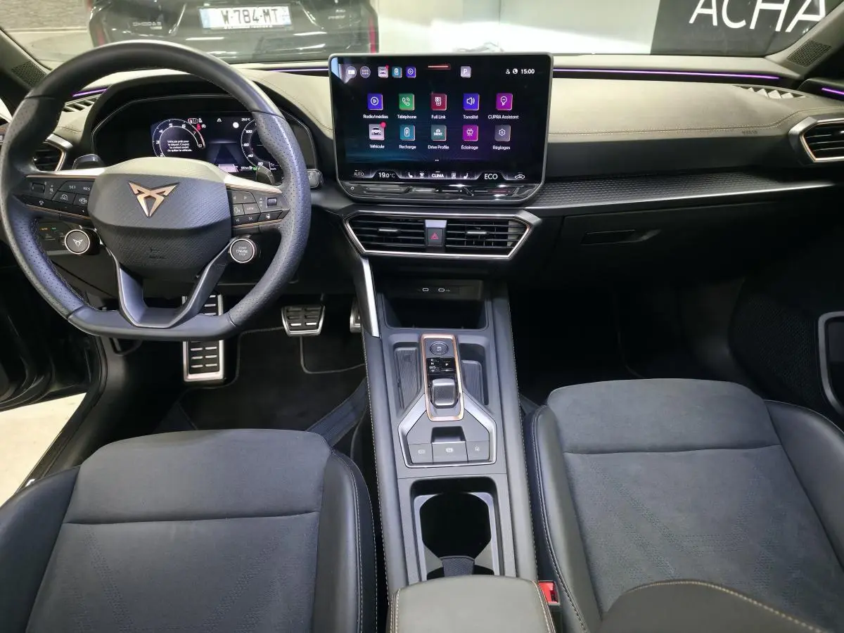 Vue intérieure avant de la CUPRA Leon 2024, volant cuir noir avec logo cuivré et écran tactile central HD.