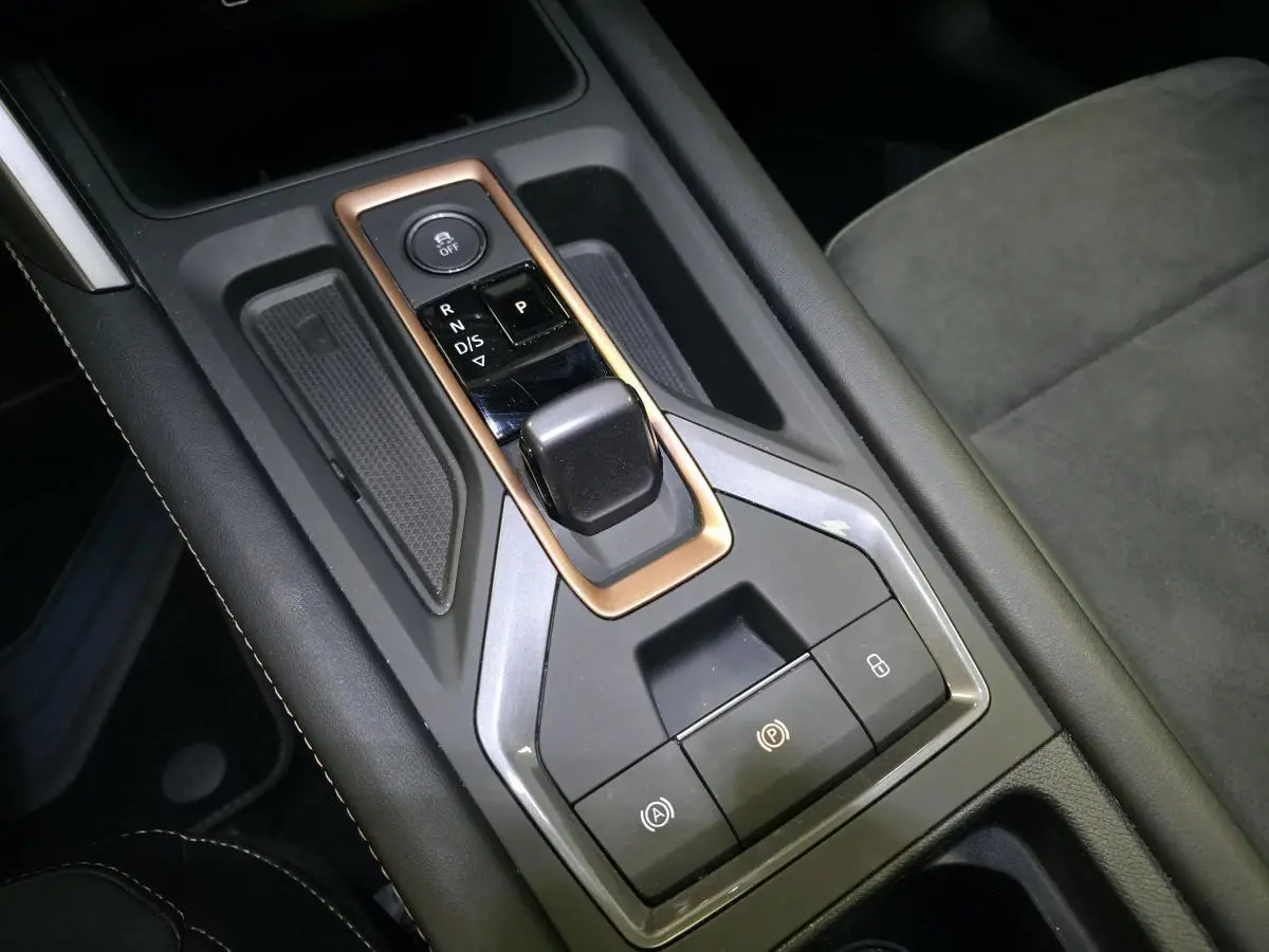 Gros plan sur la console centrale avec levier de vitesse et cadre cuivré dans l’habitacle noir du CUPRA Leon 2024.
