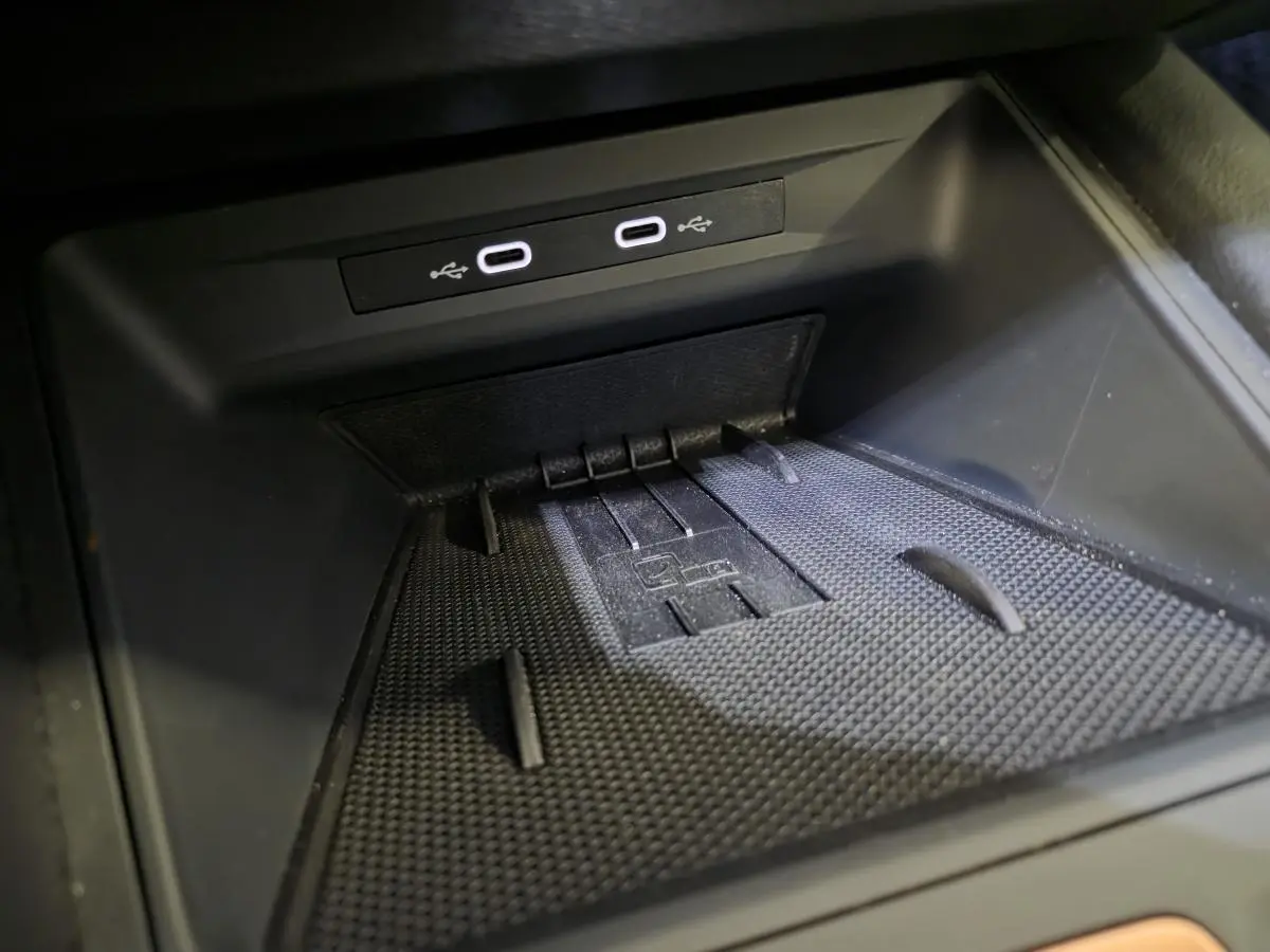Gros plan sur la zone de recharge avec deux ports USB-C éclairés dans l’habitacle noir du CUPRA Leon bleu 2024.