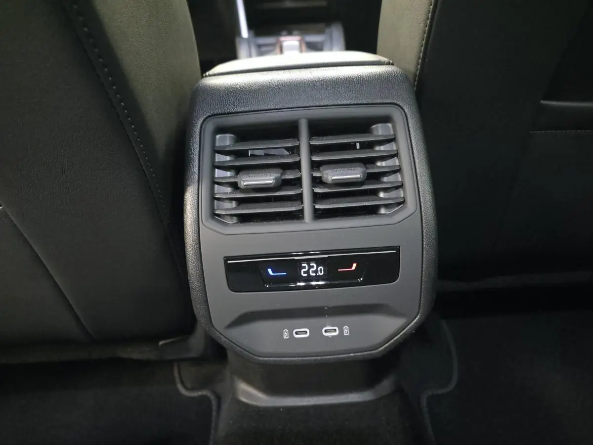 Détail de la console arrière noire avec aérateurs, affichage digital de la climatisation à 22°C et deux prises USB-C.