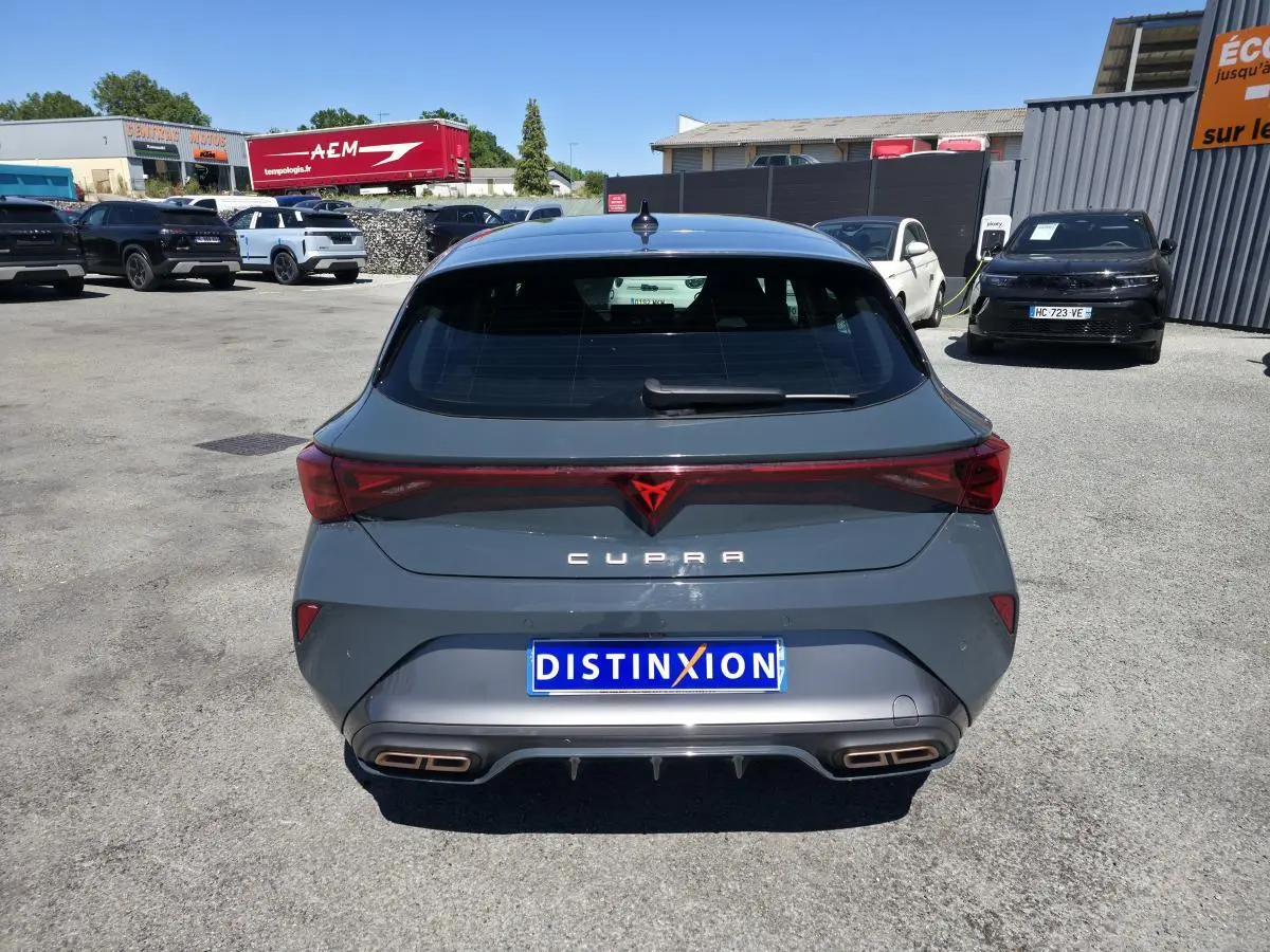 Vue arrière d'une CUPRA Leon 2024 gris foncé avec feux arrière reliés et double sortie d'échappement cuivrée.