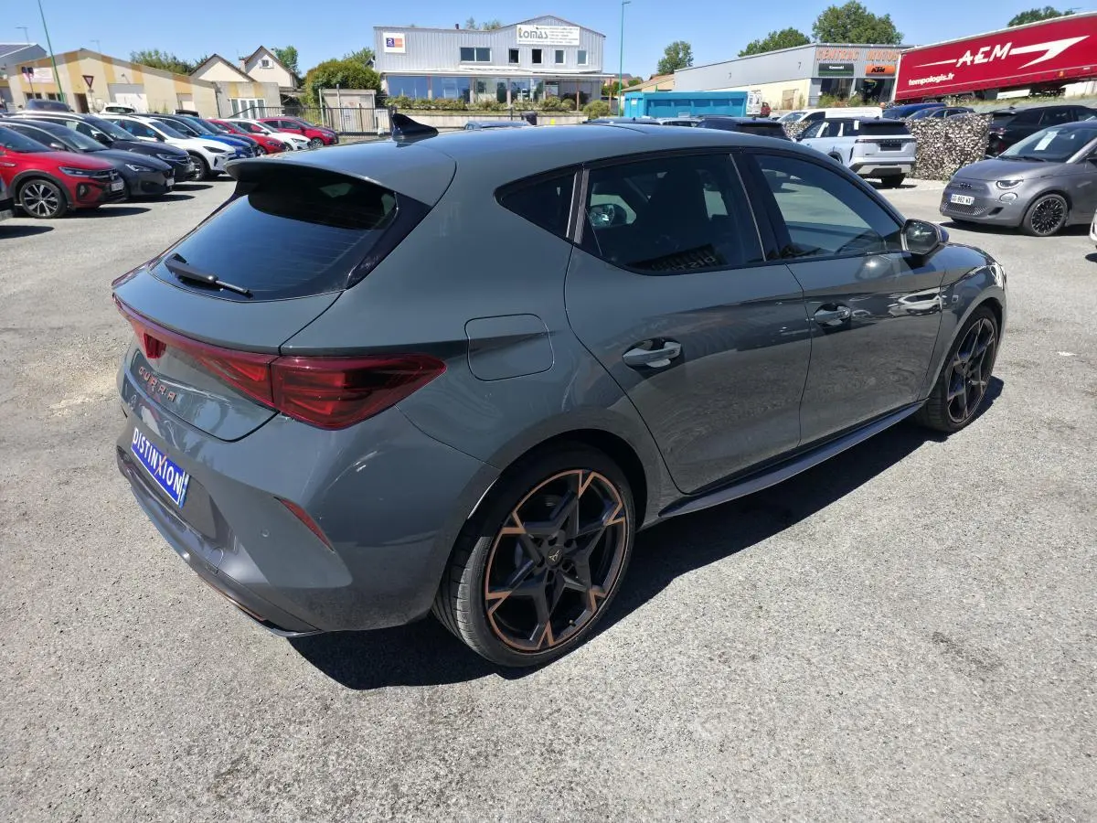Vue 3/4 arrière droite d'une CUPRA Leon 1.5 e-Hybrid 2024 bleu Fjord avec jantes alliage 19'' polar cuivrées et toit noir.