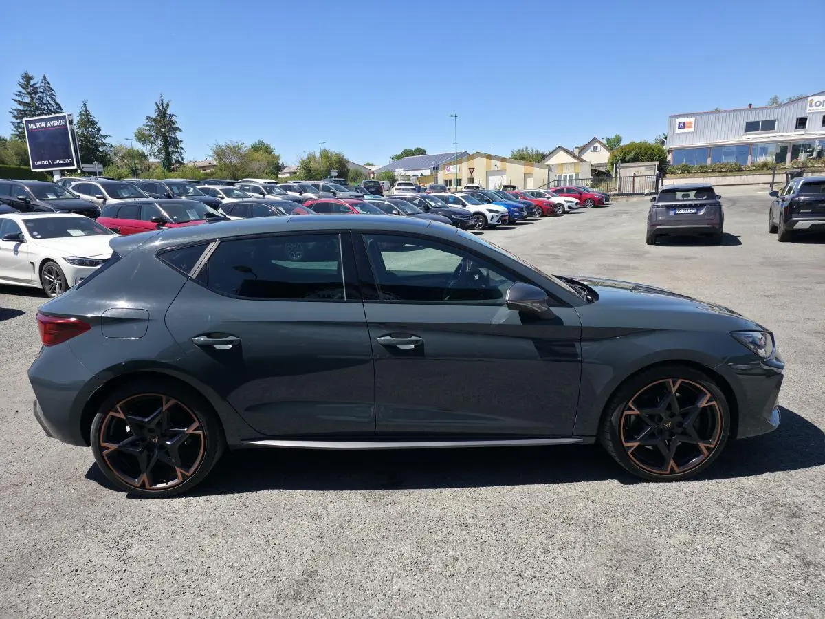 Profil droit d'une CUPRA Leon 1.5 e-Hybrid 2024 bleu foncé avec jantes alliage 19'' cuivrées et vitres surteintées.