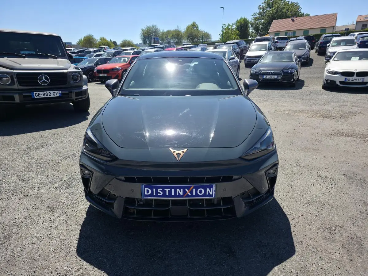 Vue avant d’une CUPRA Leon 1.5 e-Hybrid bleu avec logo cuivré et plaque Distinxion sur un parking.
