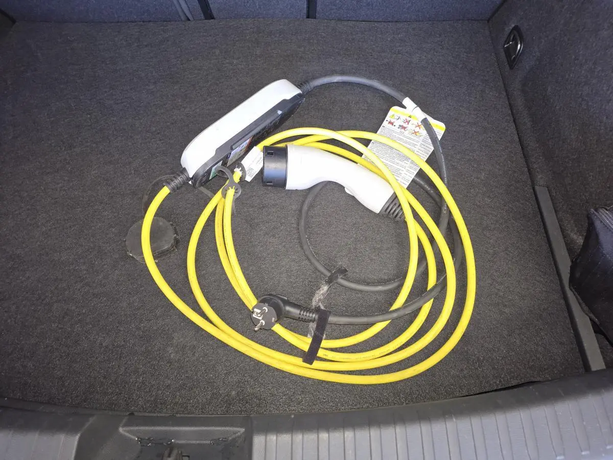 Câble de recharge hybride jaune et blanc dans le coffre d'une CUPRA Leon bleu 2024.