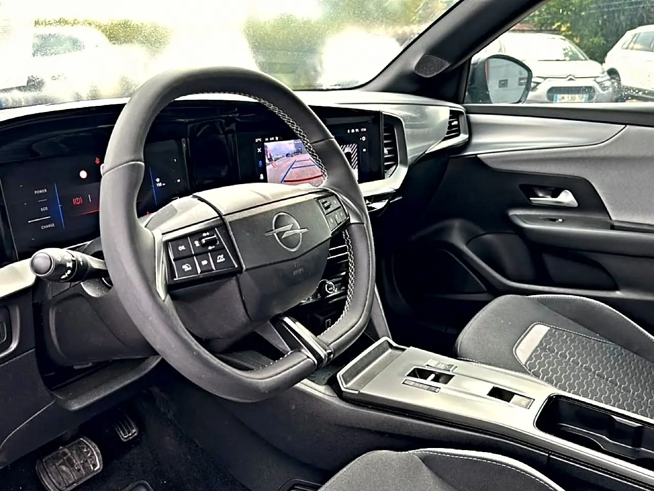 Vue intérieure de l'Opel Mokka 2025 montrant le volant multifonction, l'écran tactile et les sièges gris foncé.