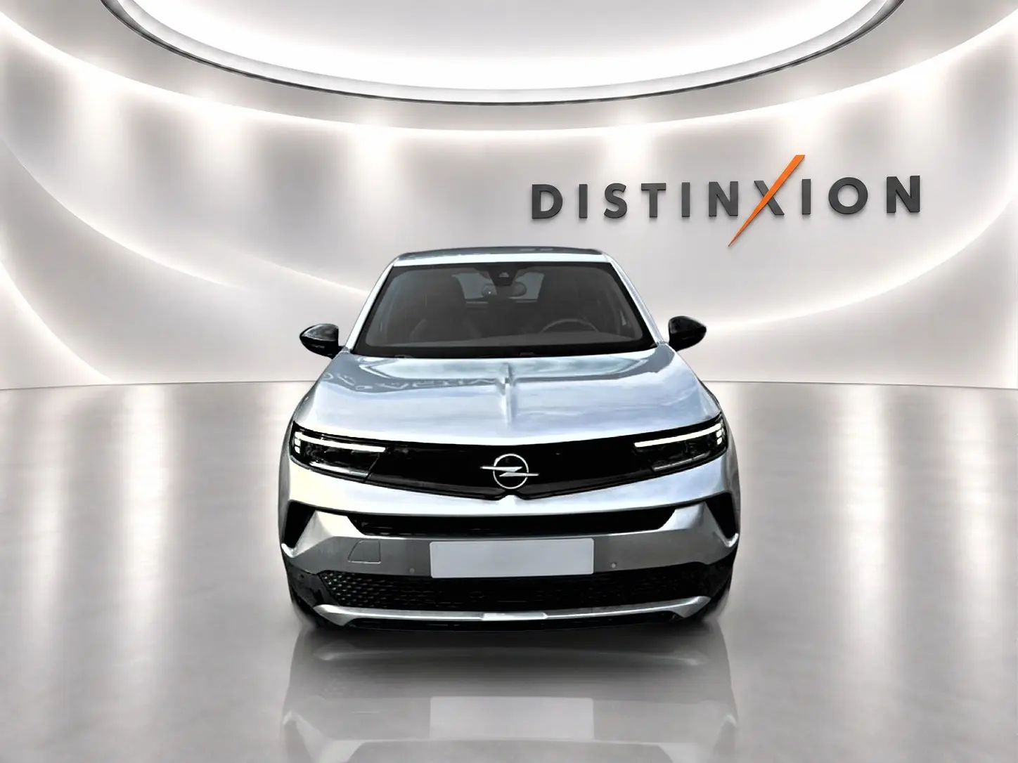 Vue frontale de l'Opel Mokka gris 2025 avec calandre noire et éclairage LED fin dans un showroom lumineux.