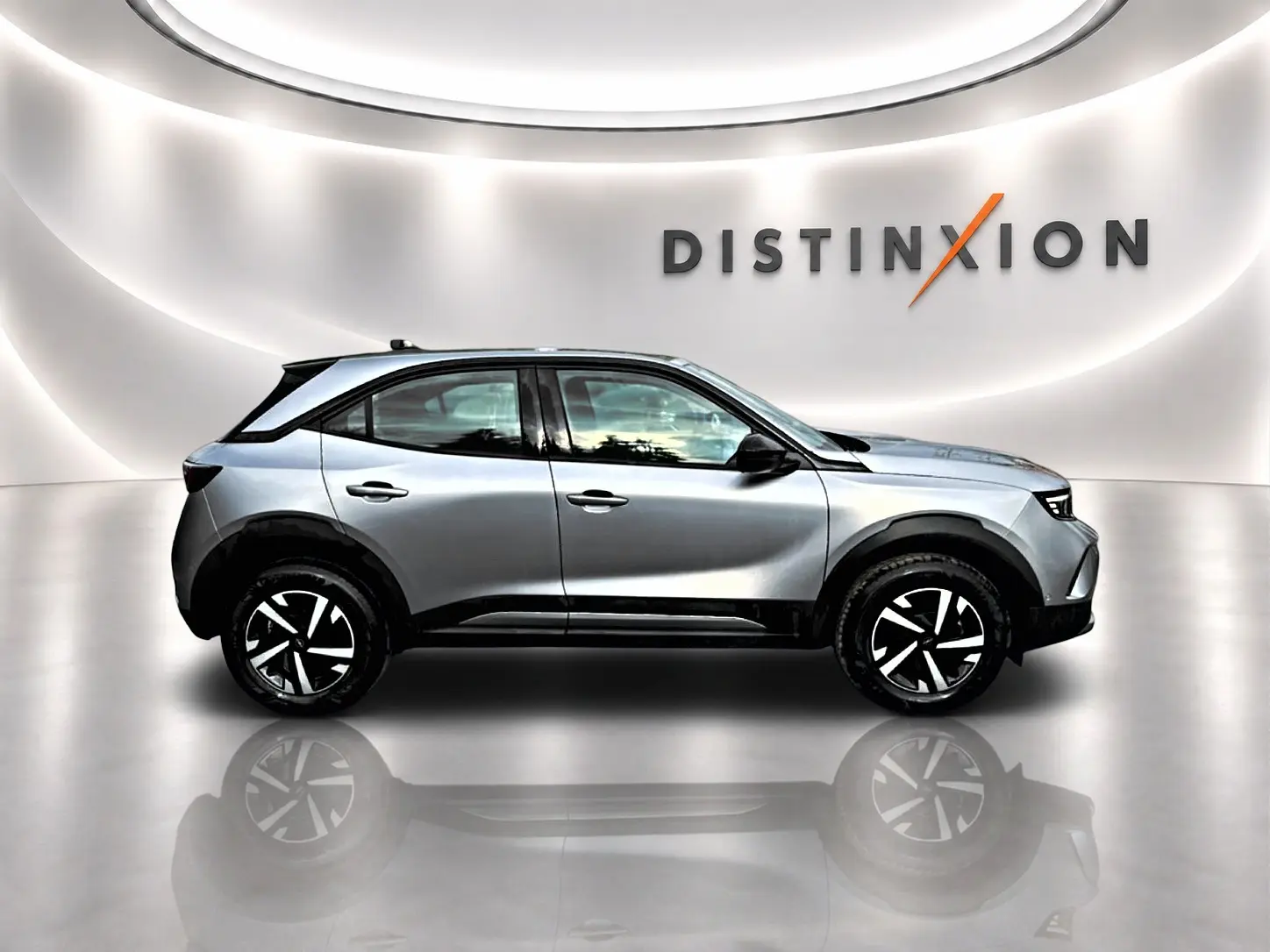 Opel Mokka gris en profil droit dans un studio lumineux avec jantes noires et blanches distinctives.