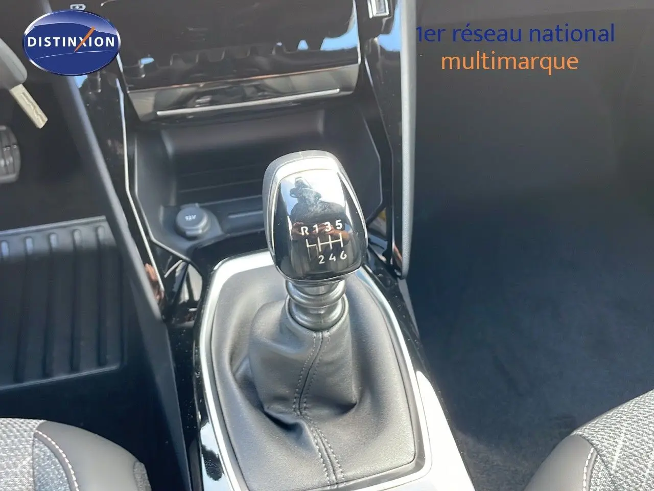 Le levier de vitesses manuel de la Peugeot 2008 gris Artense, avec console noire brillante en intérieur.