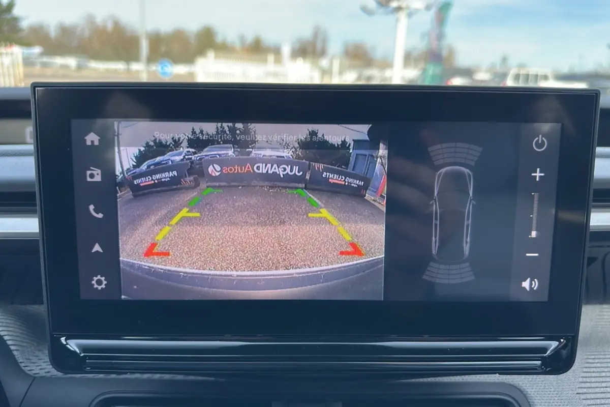 Écran tactile intérieur montrant la caméra de recul et les capteurs de stationnement d'une Citroën C3 Aircross hybride 2025.