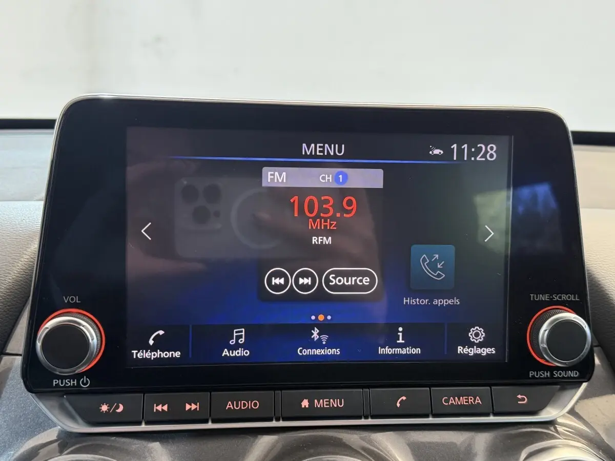 Écran tactile central du Nissan Juke Tekna 2021 affichant la radio FM 103.9 MHz avec commandes audio et téléphone.