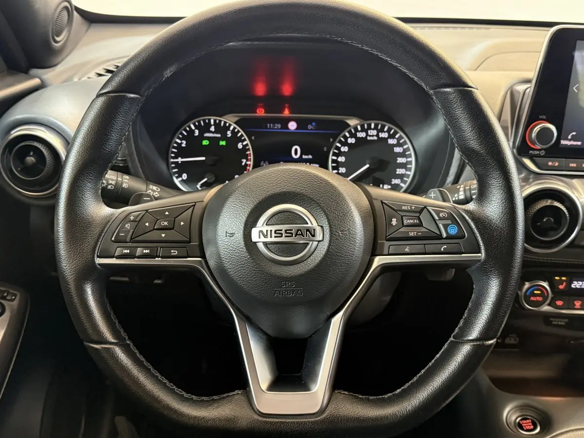 Vue rapprochée du volant cuir noir du Nissan Juke 2021 avec commandes multifonctions et tableau de bord digital.