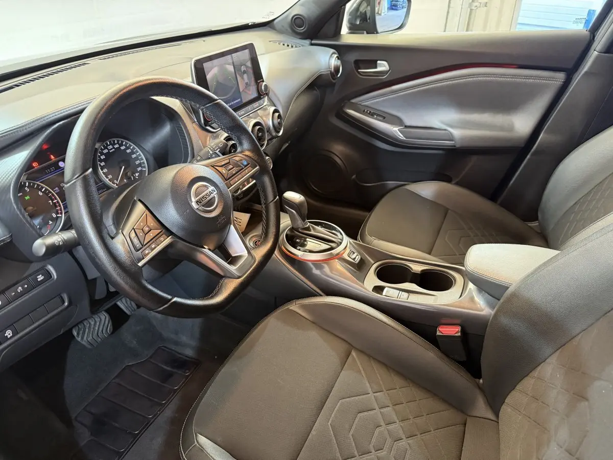 Intérieur Nissan Juke Tekna 2021 vu côté conducteur, volant cuir, console centrale avec écran tactile et sièges noirs.