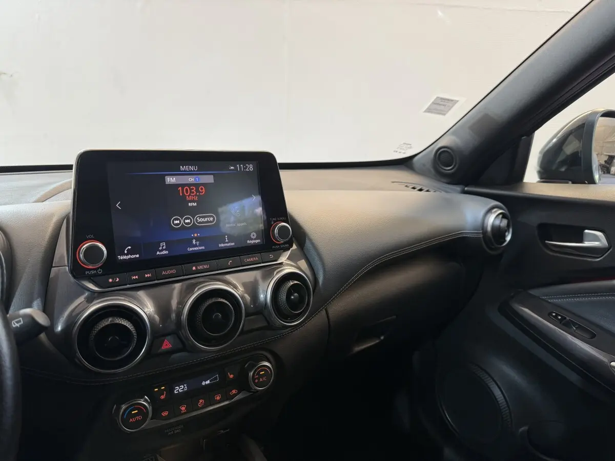 Intérieur du Nissan Juke Tekna 2021 gris clair, vue côté passager sur tableau de bord et écran tactile central.