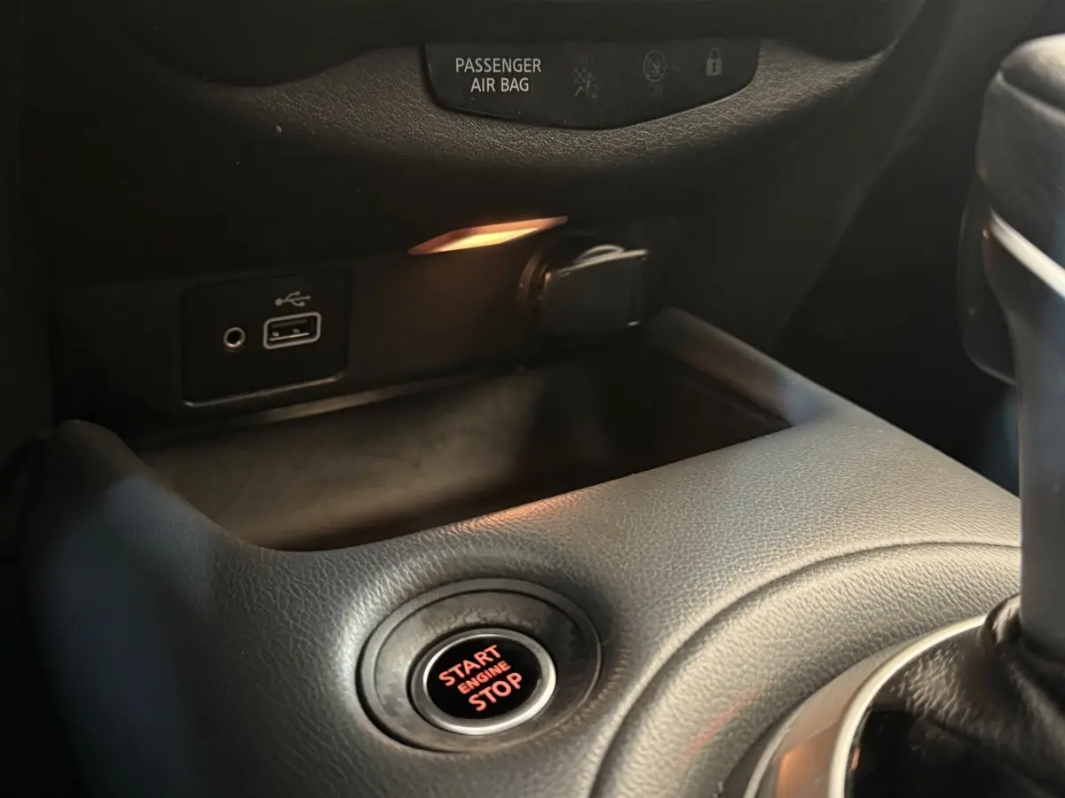 Gros plan sur le bouton démarrage rouge et les ports USB dans l'habitacle noir du Nissan Juke gris clair 2021.