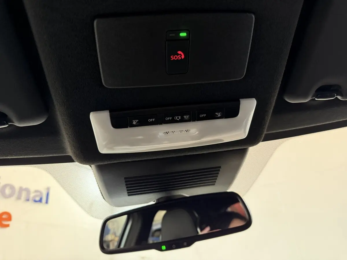 Vue intérieure du plafond avec commandes d'éclairage, bouton SOS et rétroviseur dans un Nissan Juke gris clair 2021.