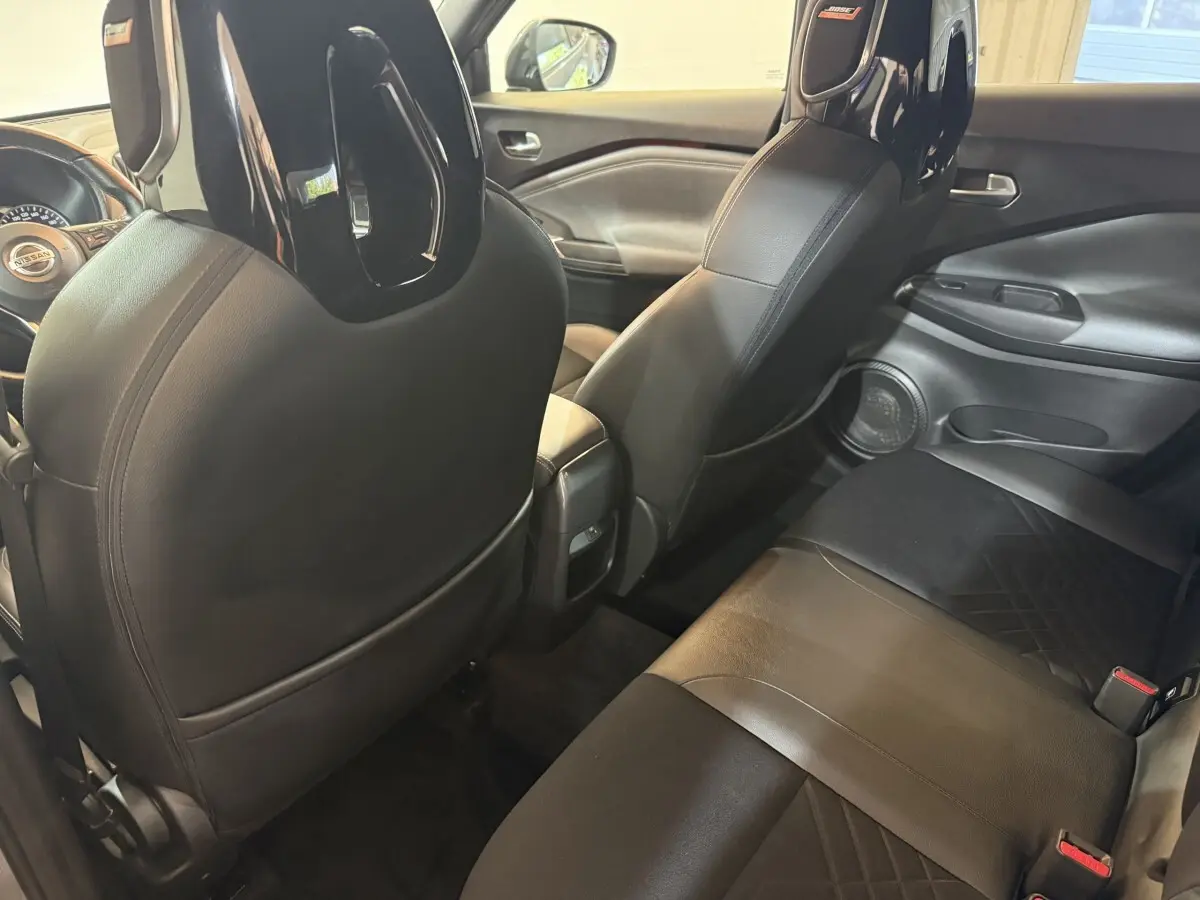 Vue intérieure arrière côté droit du Nissan Juke gris clair 2021, sièges en cuir noir avec appuie-tête Bose.