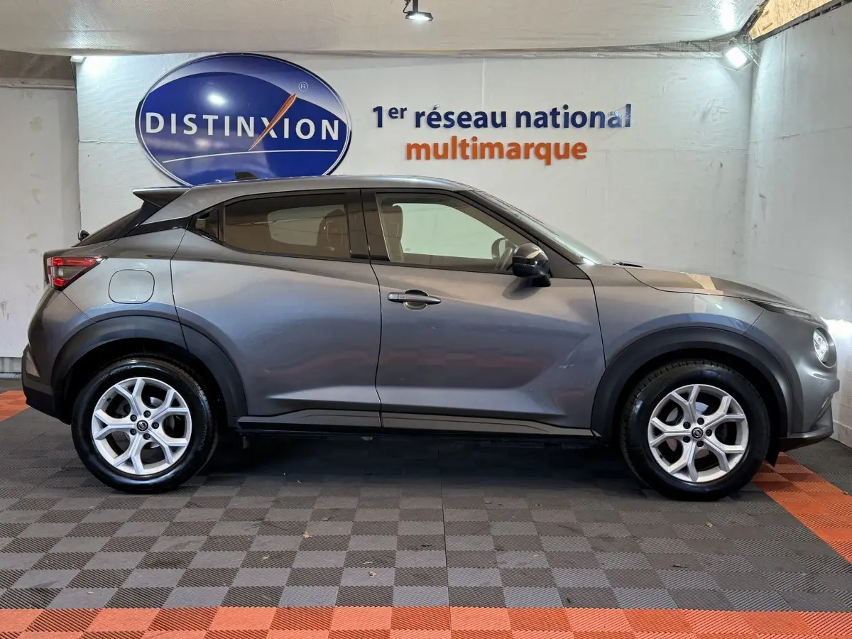 Profil côté gauche du Nissan Juke gris clair 2021, soulignant ses lignes compactes et ses jantes alliage.
