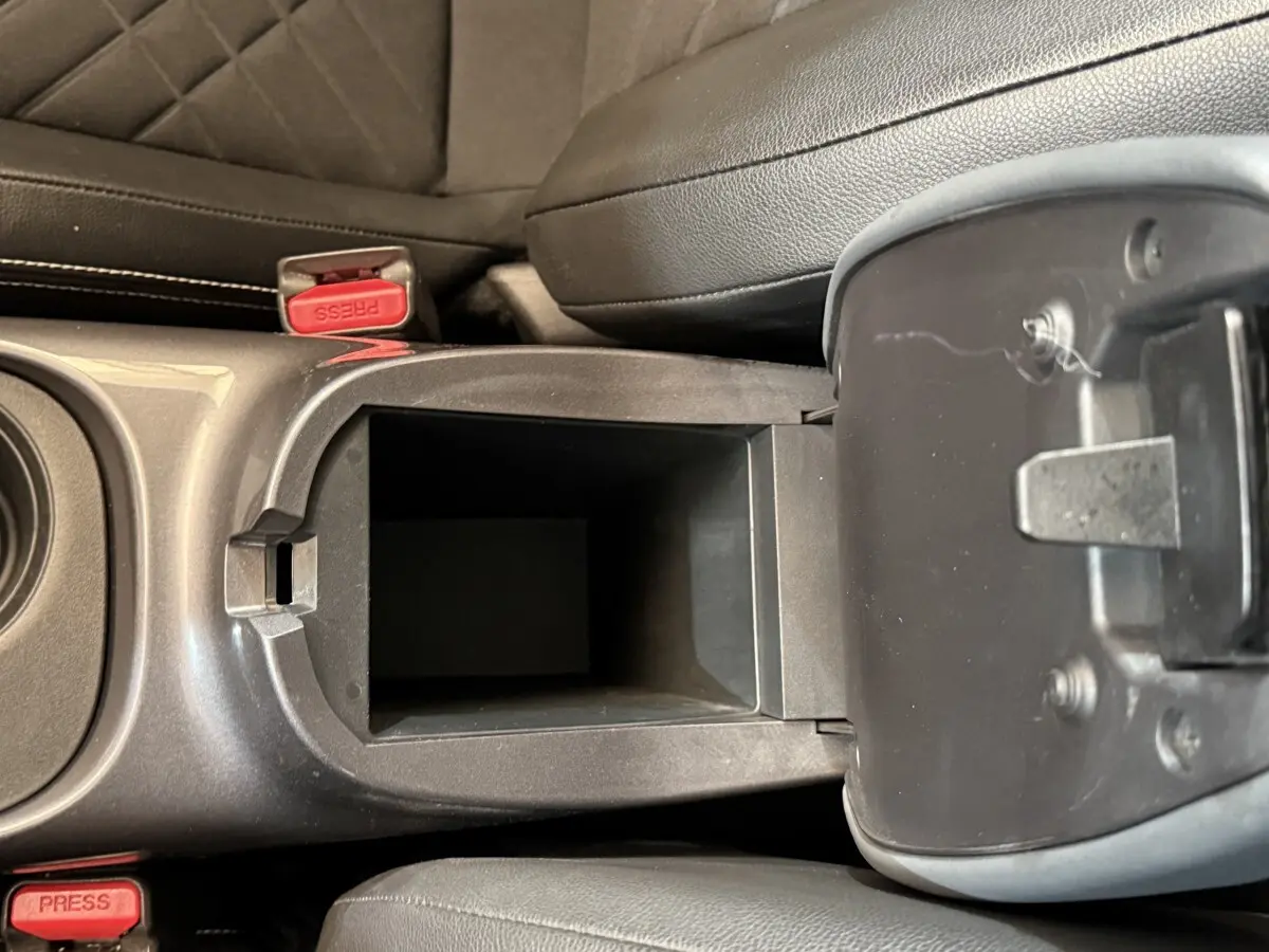 Vue plongeante sur le rangement central ouvert entre les sièges avant en cuir noir du Nissan Juke gris clair.