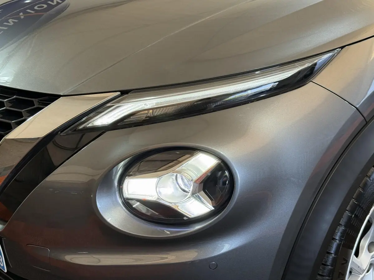 Gros plan sur le phare avant droit et la calandre d'un Nissan Juke gris clair 2021, finition Tekna.