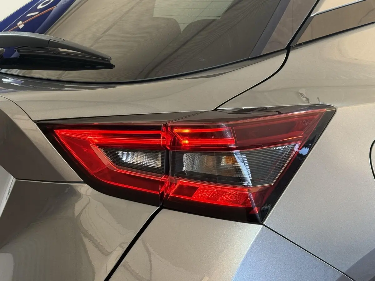 Gros plan sur le feu arrière droit rouge du Nissan Juke gris clair, soulignant les lignes anguleuses du coffre.