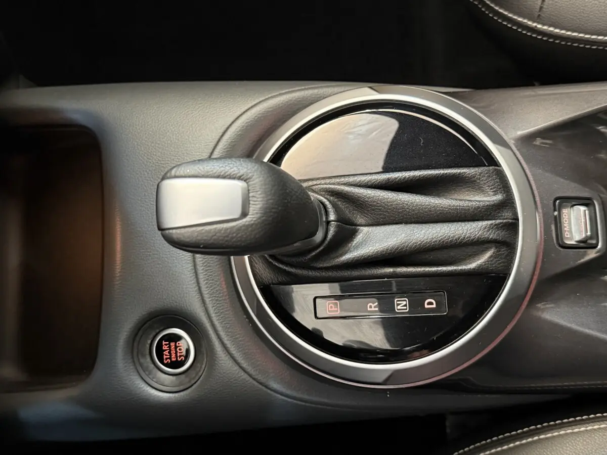 Gros plan sur la commande de boîte automatique et bouton start/stop dans le console centrale d'un Nissan Juke gris clair.