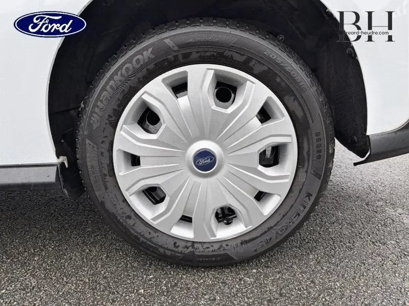 Gros plan sur la roue avant droite du Ford Transit Connect blanc glacier, mettant en valeur la jante avec enjoliveur gris.