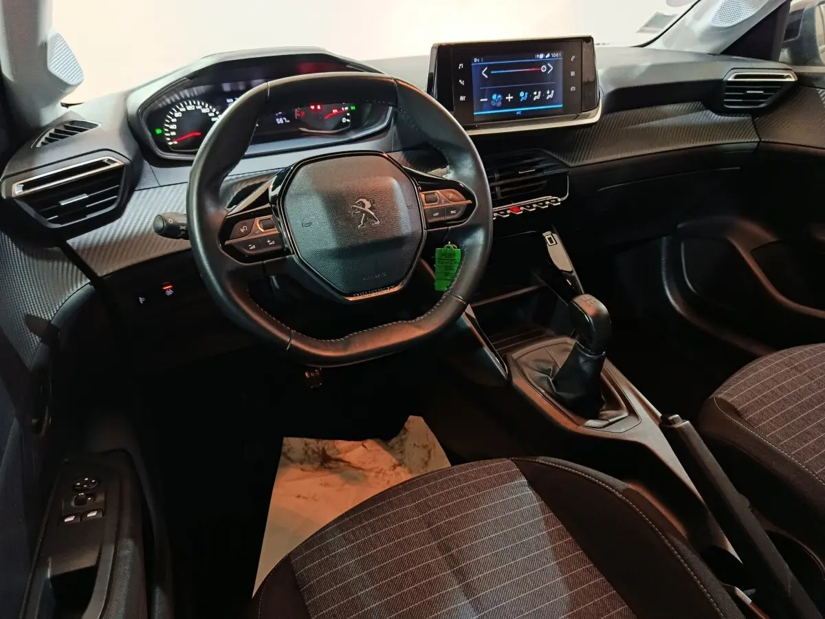 Vue intérieure avant de la Peugeot 208 1.2 PT 75 S&S Premium 2022, volant compact, écran tactile et levier de vitesses manuel.