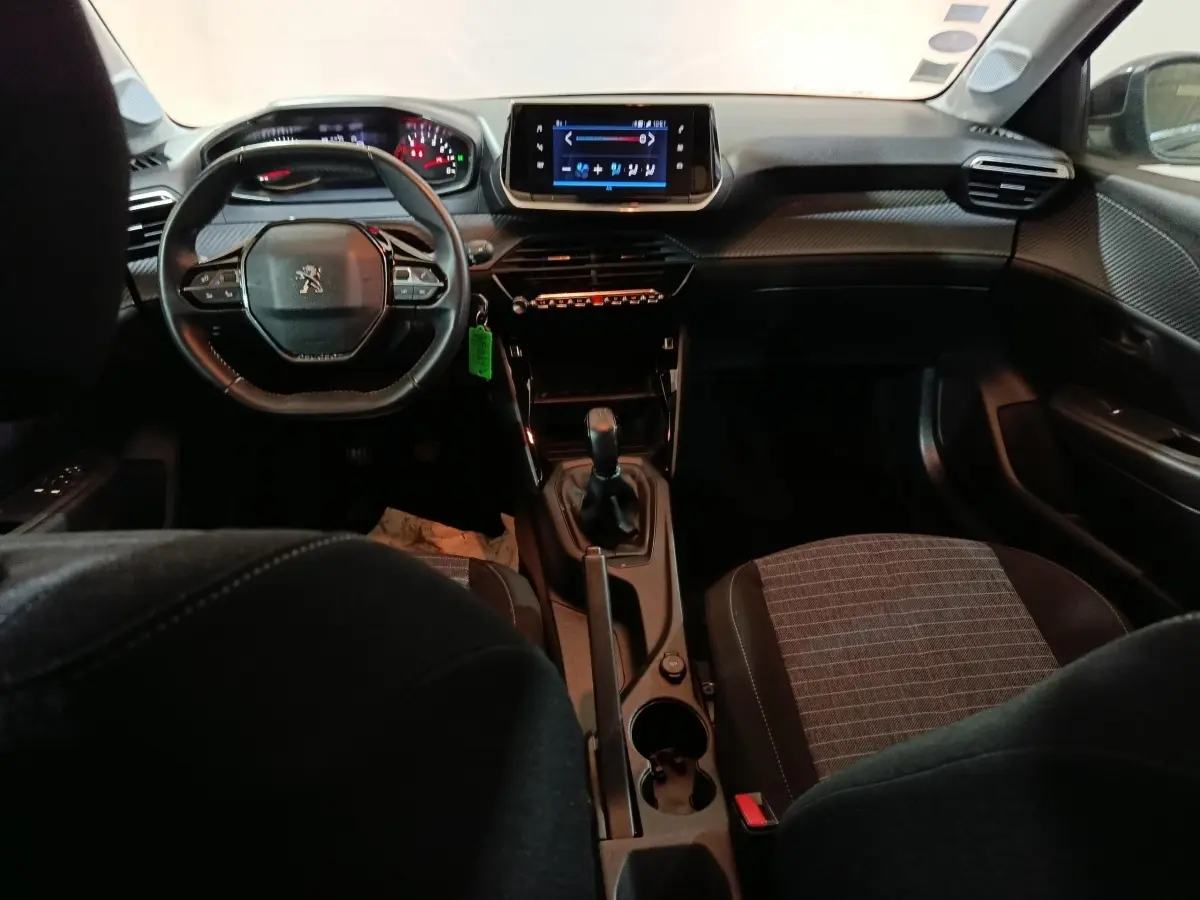 Intérieur de la Peugeot 208 1.2 PT 75 S&S Premium 2022, vue avant centrée sur le tableau de bord et volant noir compact.