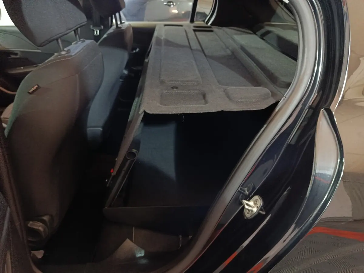 Vue intérieure côté droit du coffre ouvert avec banquette arrière rabattue d'une Peugeot 208 noire 2022.