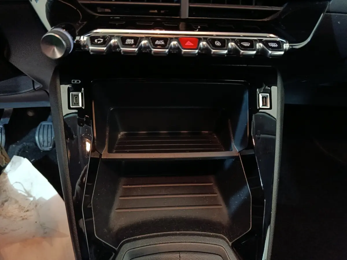 Vue rapprochée de la console centrale noire de la Peugeot 208 1.2 PT 75 S&S Premium avec ports USB et boutons de commande.