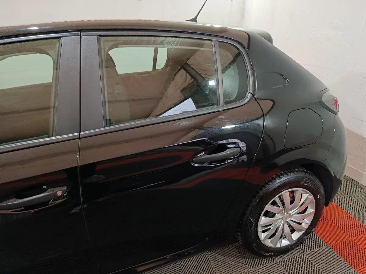 Vue latérale droite sur l'arrière d'une Peugeot 208 noire, mettant en valeur la porte arrière et la roue arrière.