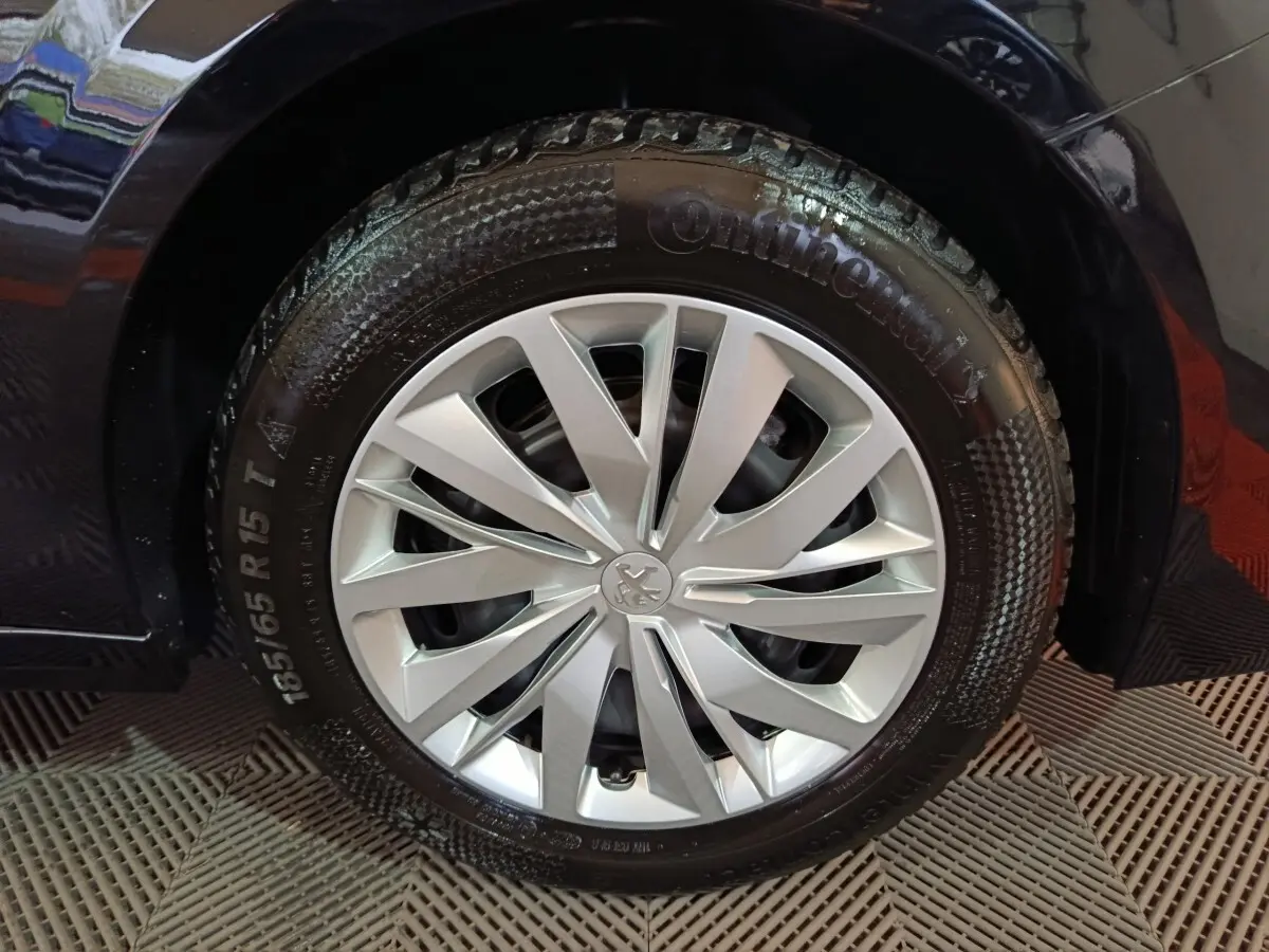 Gros plan sur la roue avant droite d'une Peugeot 208 noire de 2022 avec jante argentée et pneu Continental.