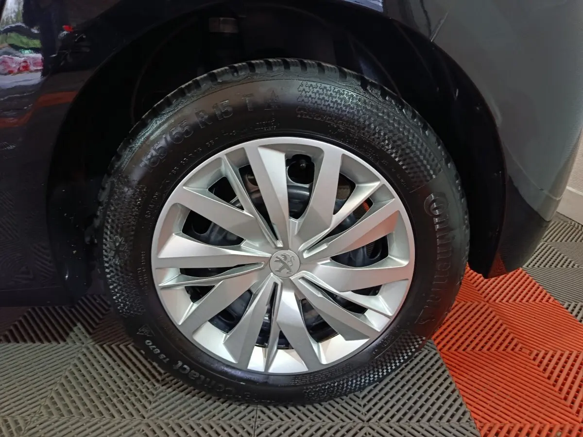 Gros plan sur la roue avant gauche de la Peugeot 208 noire, mettant en valeur la jante argentée au design moderne.