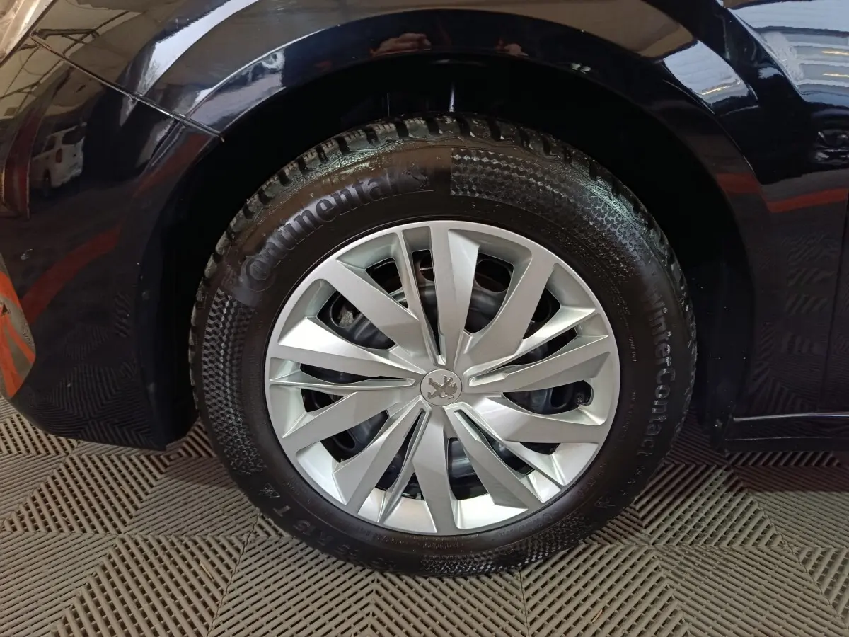 Gros plan sur la roue avant droite d'une Peugeot 208 noire, mettant en valeur la jante argentée et le pneu Continental.