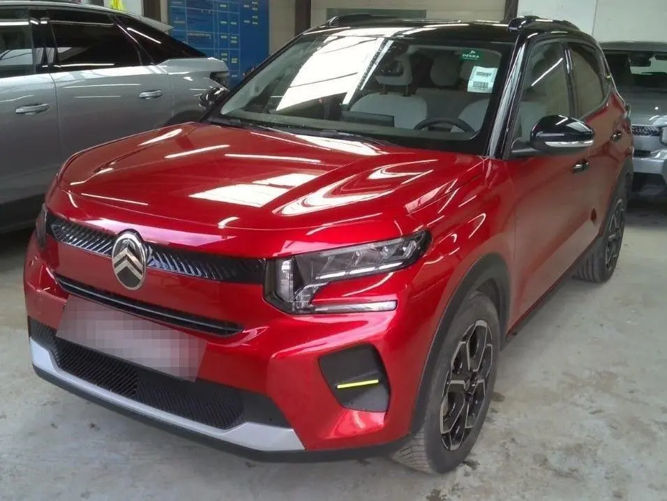 Vue 3/4 avant droite d'une Citroën e-C3 2025 rouge Elixir avec toit noir Perla Nera et jantes alliage 17 pouces.