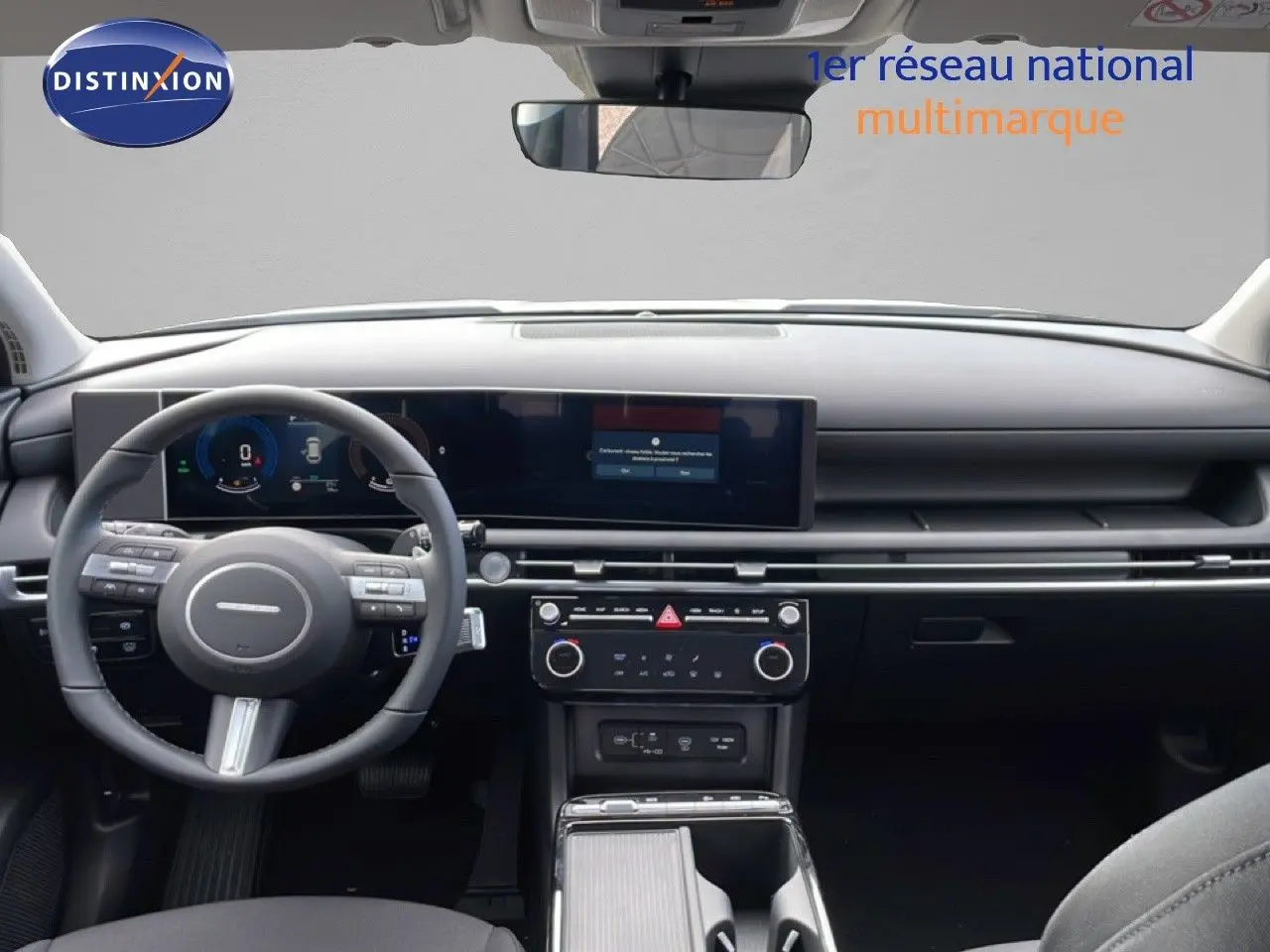 Vue intérieure frontale du tableau de bord du Hyundai Tucson blanc Atlas 2026 avec écran large et volant multifonction.