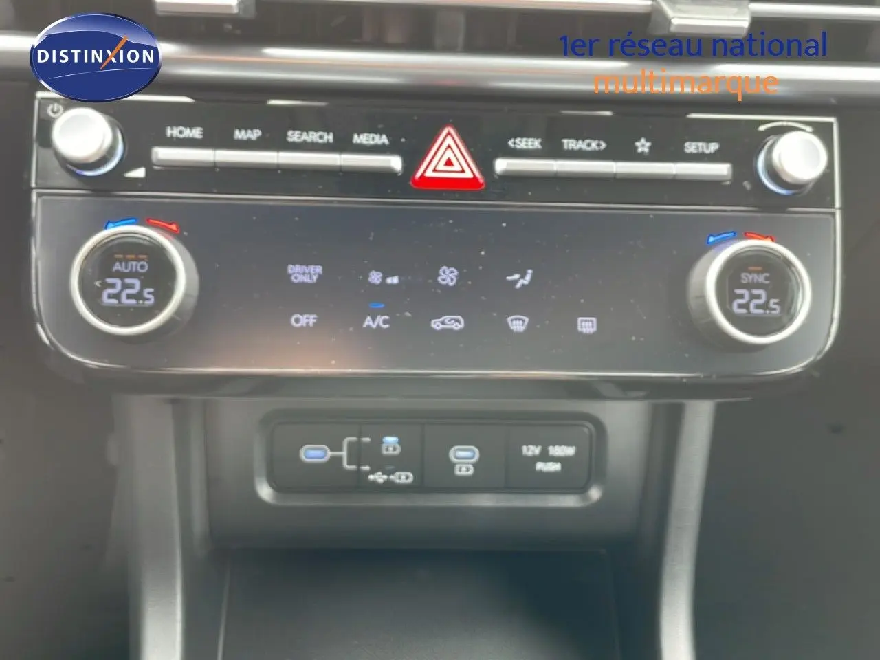 Gros plan sur la console centrale du Hyundai Tucson blanc Atlas, montrant les commandes de climatisation et les ports USB.