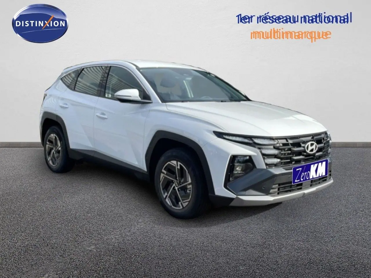 Hyundai Tucson blanc atlas en 3/4 avant droit, SUV hybride avec calandre marquée et jantes bi-ton.