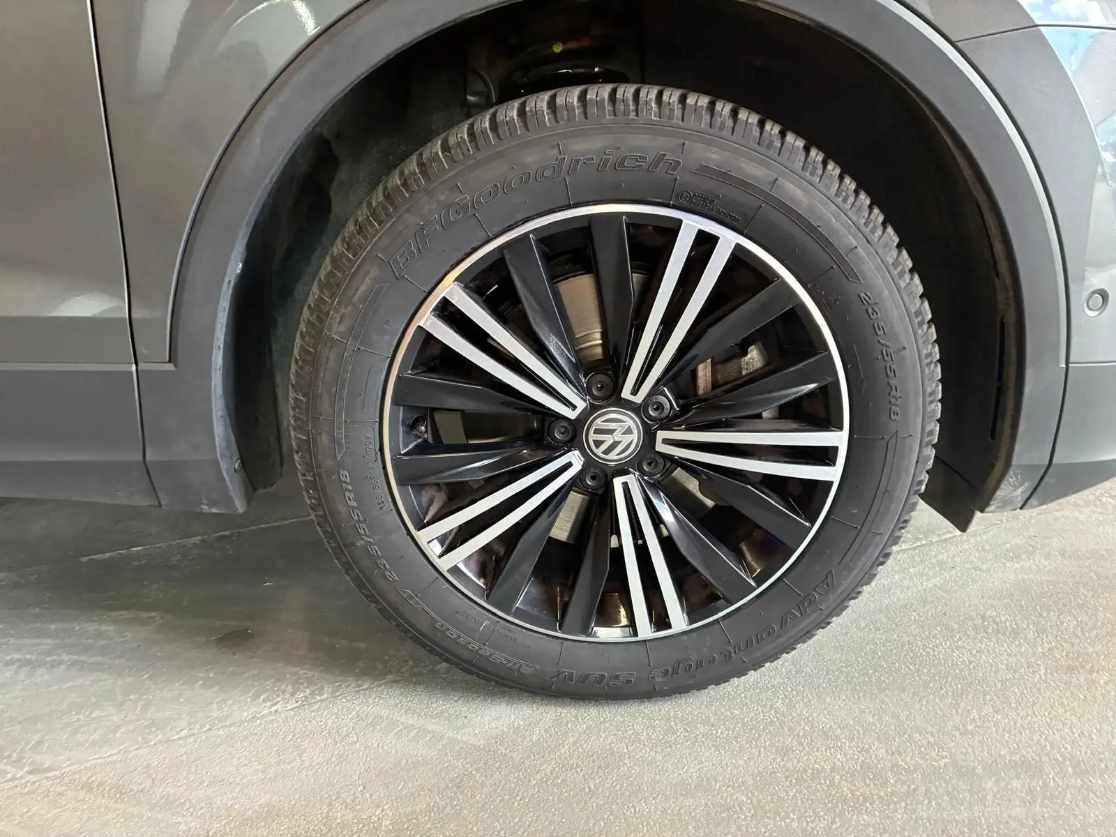 Gros plan sur la roue avant gauche d’un Volkswagen Tiguan gris, avec jante noire et argentée au design moderne.