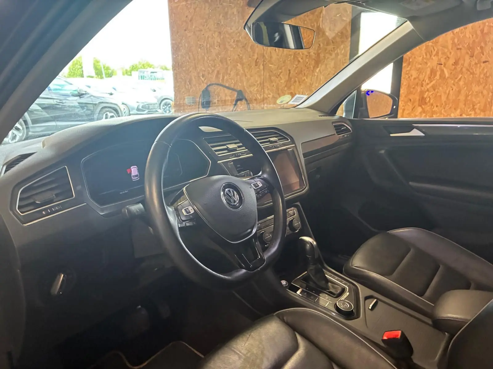 Vue intérieure côté conducteur du Volkswagen Tiguan gris 2020, avec volant cuir et console centrale équipée.